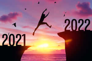 日落時分，人物從標有2021的懸崖跳到標有2022的懸崖。 — 日落 壁紙