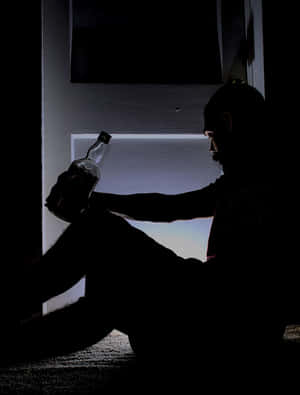 一個男人在昏暗的房間裡拿著瓶子的剪影。 — 剪影 壁紙