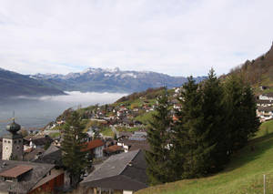 山坡上的阿爾卑斯山村，湖泊和白雪覆蓋的山峰在霧中。 — 秋天 壁紙