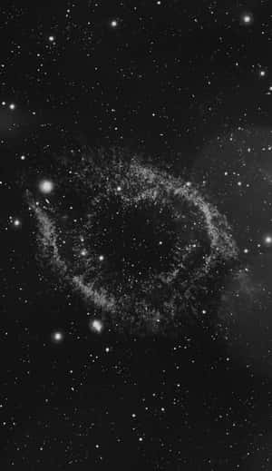 一個發光的宇宙星雲，被太空中遙遠的星星環繞。 — 簡約暗黑美學 壁紙