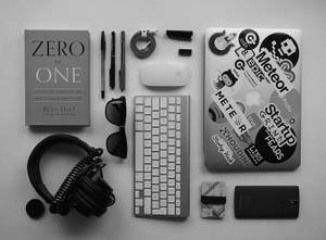 初創工作空間，有書、鍵盤、耳機和貼滿貼紙的筆記型電腦。 — 筆電 壁紙