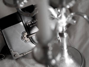 一個 Prada 手提包和華麗燭台的單色特寫。 — Prada 壁紙