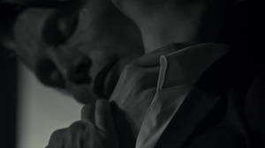 一個在陰影黑白中的人靠近，手放在衣領上，處於緊張親密的時刻。 — 漢尼拔 壁紙