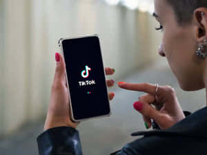 人拿著打開了TikTok應用程式的電話，並指向螢幕。 — TikTok 動圖 壁紙