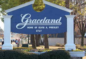 藍色 Graceland 標誌，帶有白色字體，由白色柱子框起，周圍環繞著樹木和花朵。 — 桌面 壁紙