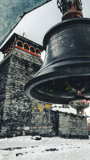 一個大型寺廟鐘掛在雪覆蓋的石塔前。 — 神之塔 壁紙