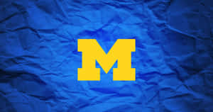 皺巴巴的藍色紙背景上的大膽黃色M標誌。 — 金鋼狼 壁紙