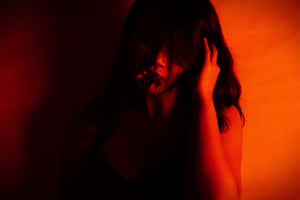 一個女人在紅光中吸煙，手靠近臉部。 — 憂鬱 GIF 壁紙