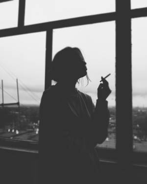 女人剪影在窗邊抽煙，俯瞰城市 — 剪影 壁紙