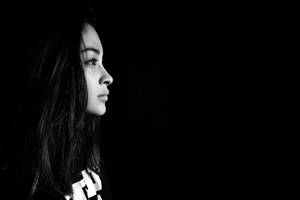 女人側面，深色頭髮，在黑色背景上強烈燈光 — 暗黑少女風 壁紙