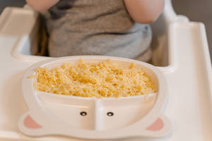 嬰兒在高腳椅上從熊形盤子吃碎食物。 — 搞笑寶寶 壁紙
