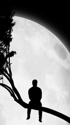 夜晚，一個人影坐在樹枝上，下方是一輪巨大的月亮。 — 月光 壁紙
