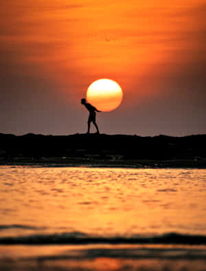 日落時分站在海灘上的人影，橙色天空和水面 — 夕陽天空 壁紙