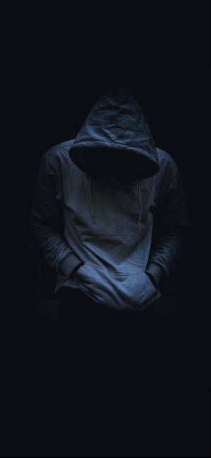 一個穿連帽衫的人在黑暗中低著頭，雙手插袋。 — 男人 壁紙