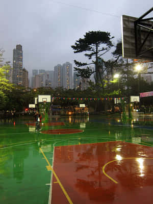 夜晚在濕滑球場打籃球的人，背景是城市天際線。 — 春天花朵 壁紙