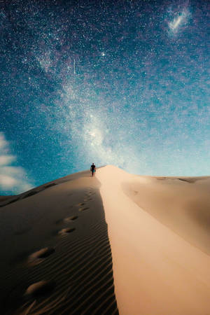一個人在星空夜空下走上沙丘，銀河可見。 — 沙漠 壁紙
