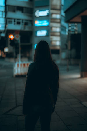 在發光的霓虹燈招牌下，夜晚的城市街道上獨自站立的剪影人物。 — 城市 壁紙