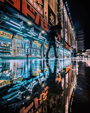 霓虹燈光反射在濕漉漉的柏油路上，一個人夜晚在東京的雨街上行走。 — 霓虹燈 壁紙