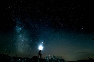 人在星空下手持手電筒，銀河可見 — 星空動畫 壁紙