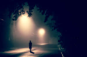 一個人在發光的街燈下，獨自走在霧濛濛的夜街上。 — 孤獨 壁紙