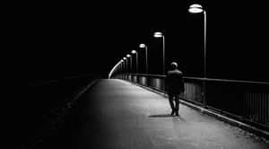 一個人在夜晚獨自走在有照明的橋上。 — 獨自一人 壁紙