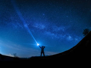 人從山丘將手電筒照向星空 — 霓虹燈 壁紙