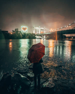 夜晚城市燈光下，河邊拿著紅色雨傘的人。 — 下雨 壁紙