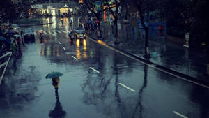 夜晚在濕漉漉的城市街道上，一個人撐著雨傘獨自走在雨中。 — 河內 壁紙