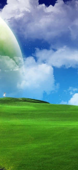 一個人在藍天下的草坡上，有一顆發光的行星 — 自然 iPhone 壁紙