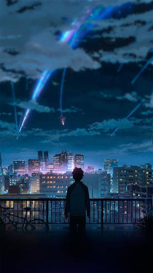 一個男孩在屋頂陽台上觀看發光的流星在夜間劃過城市天際線。 — 你的名字 GIF 壁紙