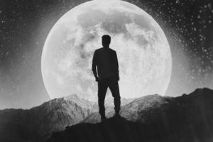 一個人的剪影站在山頂上，下方是巨大的月亮和星星。 — 月光 壁紙