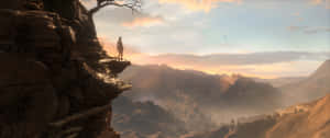 一個人在日落時分站在懸崖上，俯瞰著廣闊的山谷。 — 古墓奇兵：崛起 壁紙