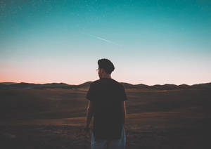 一個剪影中的男人站在沙漠中，觀看暮色天空中的流星。 — Chill 壁紙
