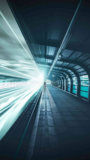 一個人在列車月台上等待，光線條紋在隧道中模糊掠過。 — 地鐵 壁紙