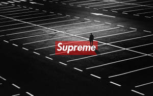 一個孤獨的人站在空曠的停車場，帶有紅色Supreme標誌。 — 紅色至尊 壁紙