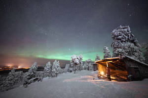 夜晚在北極光下站在雪覆蓋的小屋中的人 — 芬蘭 壁紙