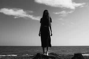 女人赤腳站在海邊岩石上，天空多雲 — 黑暗自然 壁紙