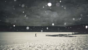 一個人在夜晚獨自走在結冰的湖面上，雪花飄落。 — 孤獨悲傷 壁紙