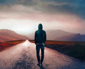 穿連帽衫的人沿著長路走向暮色中的山脈。 — 獨自一人 壁紙