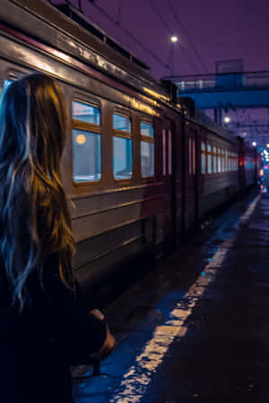 女子在紫色天空下夜晚雨中的火車站等候。 — 地鐵 壁紙