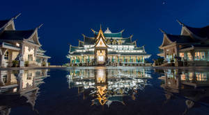 一個雄偉的寺廟建築群在夜晚發光，水面倒影完美，月亮高掛。 — 會長是女僕大人 壁紙