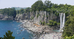 海岸瀑布，遊客在岩石海岸上 — 제주도 壁紙