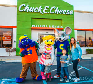 家庭與Chuck E. Cheese吉祥物在餐廳外日落時分。 — 查克芝士 壁紙