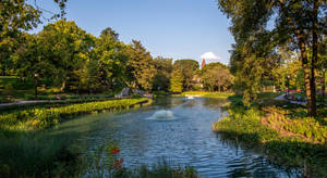 公園內一條寧靜的運河，有樹木和噴泉，在清澈的藍天下。 — 湖泊 壁紙