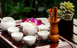 白色瓷茶具套裝，帶有紅色印章，放在木托盤上，旁邊是蘭花和多肉植物。 — MacBook Pro M1 壁紙