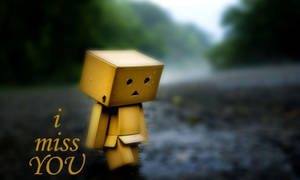 一個黃色紙箱角色站在雨中，帶有文字 i miss YOU — 悲傷語錄 壁紙