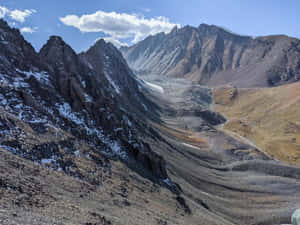 崎嶇的山谷，有雪斑和蜿蜒的河流，在藍天下。 — 丘陵景觀 壁紙