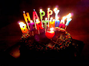 一個巧克力生日蛋糕，在黑暗的房間裡有點燃的蠟燭拼出 happy birthday。 — 生日快樂蛋糕 壁紙