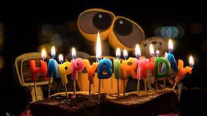 巧克力蛋糕，配有點燃的生日蠟燭和背景中的機器人玩具。 — 今天是我的生日 壁紙