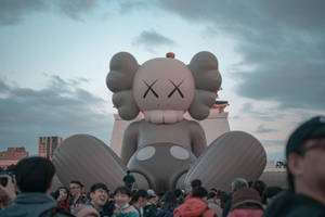 人群在黃昏時聚集在巨大的KAWS氣球周圍。 — Kaws 桌布 壁紙